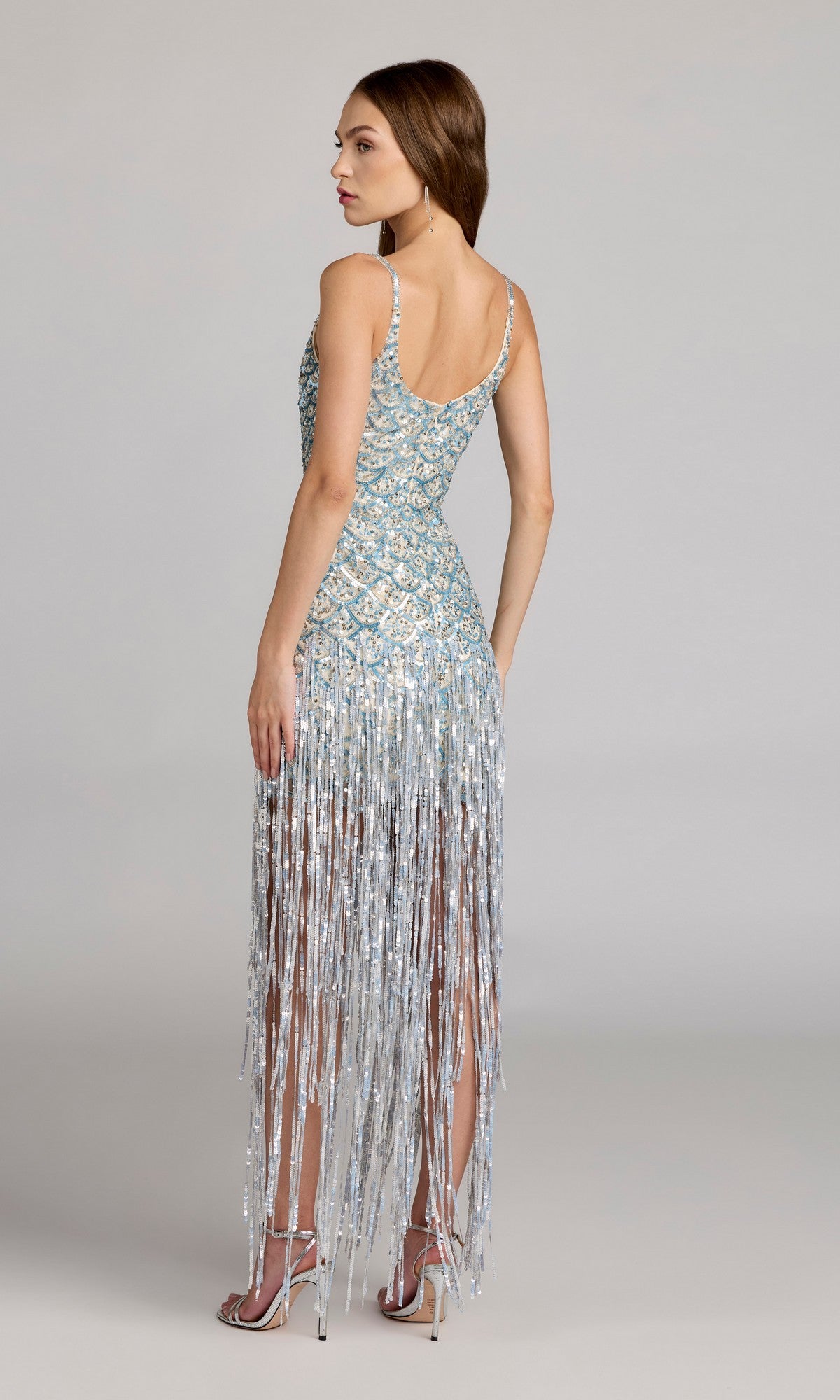 Woman in the Long Formal Dress: Mac Duggal 6251 with sequins and fringe, wearing heels, stands against a plain background, back to the camera.